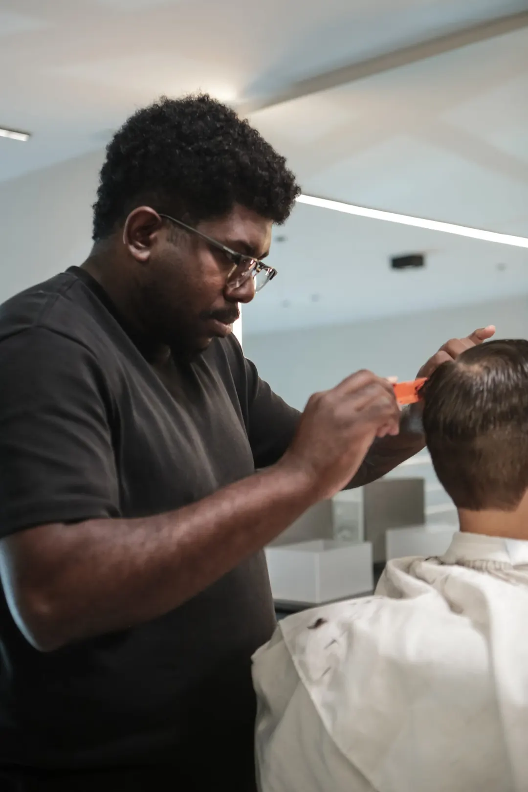 Barbeiro da Tribe cortando o cabelo de um cliente com máquina e pente