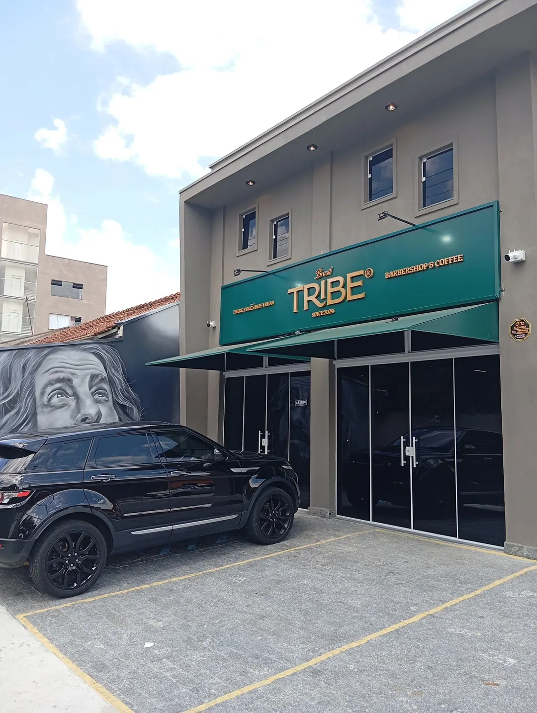 Fachada verde e dourada da Tribe Barbershop na Av. Francisco Barreto Leme, em Taubaté