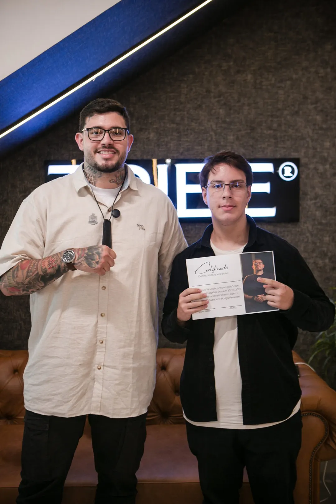 Rodrigo, barbeiro da Tribe e instrutor da Tribe Barber School, com certificado na mão